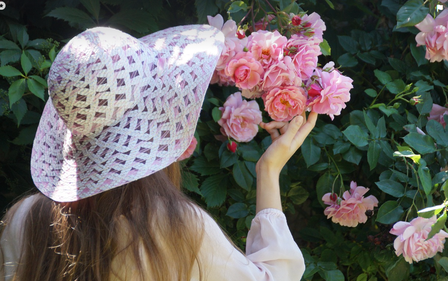 Fille à chapeau contemplant les rosiers